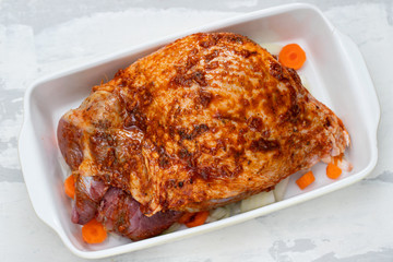 raw turkey leg with spices and vegetables on dish on ceramic background