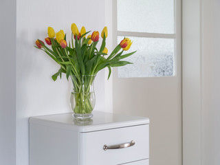 Bouquet of red and yellow tulips on a white sideboard