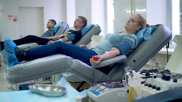 People are donating blood while lying in medical armchairs