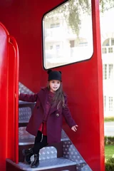Foto op Plexiglas Klein vrolijk meisje in de buurt van de rode Engelse bus in een mooie jas en een hoed. De reis van het kind. Schoolbus. Londen rode bus. De lente. Met de Internationale Vrouwendag. Sinds 8 maart! © stock_studio
