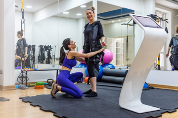 Fototapeta na wymiar Working together to improve muscle strength and tone. Athletic woman during functional workout with electric muscle stimulation in fitness gym