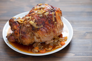 baked turkey leg with vegetables and herbs on white dish