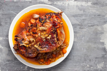 baked turkey leg with vegetables and herbs on white dish
