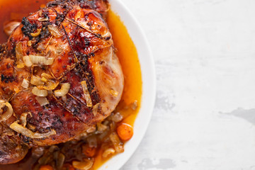 baked turkey leg with vegetables and herbs on white dish