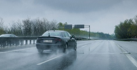 Black car traveling through heavy rain on a highway