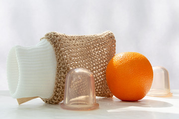 An orange is on the table and next to it are vacuum cans and a mesh washcloth made from natural...