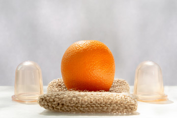 The orange lies on a mesh washcloth made from natural fibers, and next to it are vacuum banks.