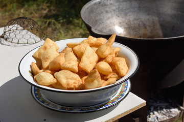 Fresh deep fried dough called Baursaki next to outdoor Qazan cauldron in Shymkent Kazakhstan
