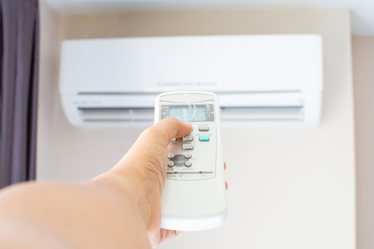 human hand press on remote control of Air Conditioner with hot weather. Subject is blurred.