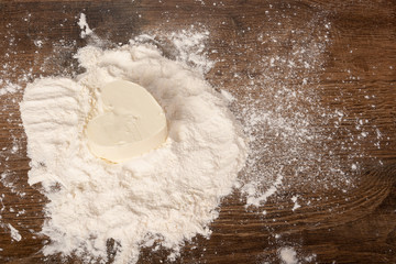 White butter or margarine in the shape of a heart in flour on a wooden table. Dough preparation for cookies, pies, cakes, pizza. Flat Lay, Copy space, space for text.