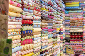 Beautiful Indian coloured cloth fabric folded on shelves for sale at Global Village creating a nice background viewed from an angle