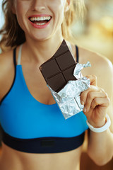 Closeup on woman with chocolate bar in modern living room