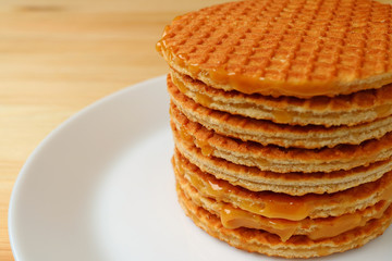Stack of Mouthwatering Stroopwafels on the White Plate Served on Wooden Table