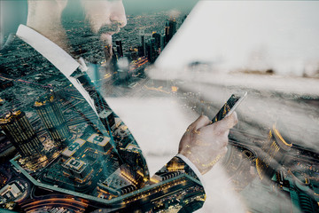 Close up of businessman using smart phone and waiting for train to come. Business trip concept. Double exposure technique used.