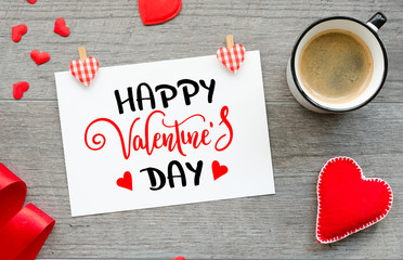 Happy valentines day lettering romantic postcard with felt hearts, red ribbon and coffee mug. Top view
