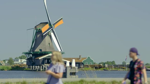 Mills of Koog aan de Zaan in Netherlands in the background  while out of focus people move in the foreground.