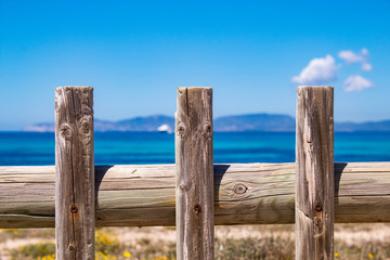 Typical balearic natural reserve vooden fence, and blue mediterranean sea on the background; Formentera Island, Spain