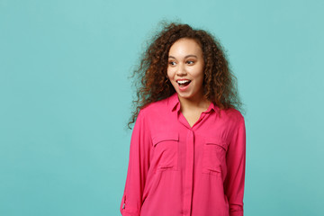 Fototapeta premium Excited african american girl in casual clothes keeping mouth open, looking aside isolated on blue turquoise wall background in studio. People sincere emotions, lifestyle concept. Mock up copy space.