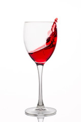 Red wine splash in a glass on white background