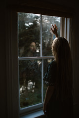 sad woman looking out window in home - 265498586