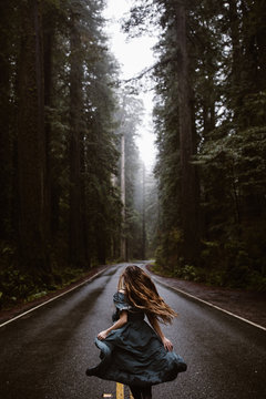 woman in blue dress on road in forest redwoods