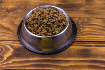 Obraz na płótnie Canvas Dry cat food in bowl on wooden background. Pet food on wood surface
