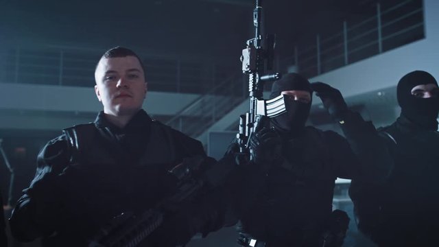 Masked Team of Armed SWAT Police Officers with Rifles are Posing After a Successful Office Building Siege. Soldiers Stand in a Row. Raise Firearms Up in the Air and Remove their Masks.