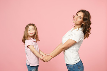Woman in light clothes have fun with cute child baby girl. Mother, little kid daughter isolated on pastel pink wall background, studio portrait. Mother's Day, love family, parenthood childhood concept
