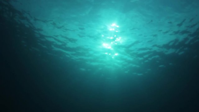 Underwater background video of sunburst on ocean surface with sunbeams  