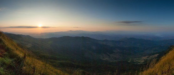 Mountain view morning above many hills and green forest around with soft fog with colorful red sun light in the sky background, sunrise at top of Phu Langka Forest Park, Phayao, Thailand.