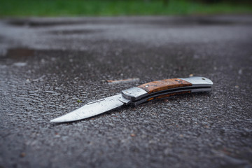 Folding knife on wet asphalt.