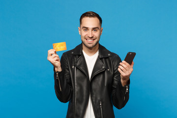 Handsome fun stylish young unshaven man in black jacket white t-shirt hold in hand cellphone,...