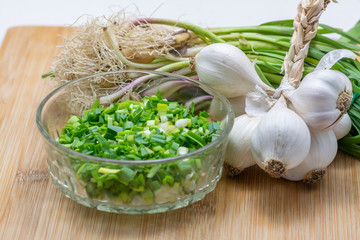 Raw green garlic on cutting board preparated for cooking.