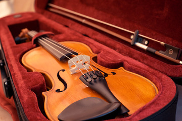 Fototapeta premium Violin and bow in dark red case. Close up view of a violin strings and bridge
