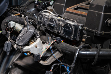 Fototapeta premium Car interior in the back of a van with a disassembled dashboard and view on shift gear and climate-control during preparation in a vehicle repair workshop. Auto service industry