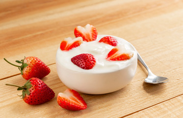 Bowl of yogurt and red fruit strawberry on the wood table.