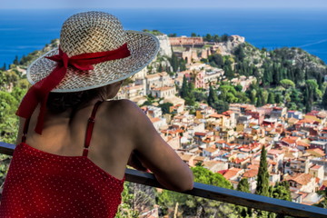 Fototapeta premium Frau mit Sonnenhut blickt auf Taormina, Sizilien