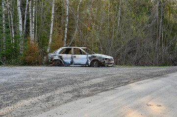 Obraz na płótnie Canvas a burnt down car at a gravel road