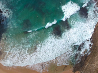 Aerial view of sandy beach with waves and clear ocean water. Drone photo