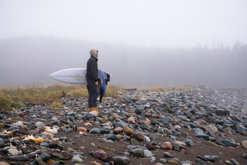 Side view of man with surfboard standing on beach