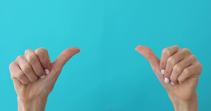Woman hands pointing on copyspace and showing thumbs up over yellow background