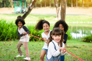 Group of children playing tug of war at the park