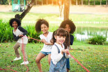 Children playing tug of war at the park, Group of children in a field trips.