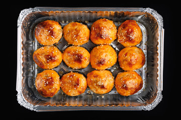 baked sushi rolls in a foil box container