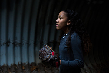 Side view of girl wearing softball glove in tunnel