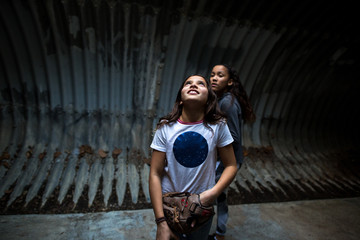 Girl wearing softball glove looks upward in tunnel