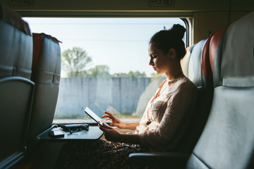 Side view of woman using digital tablet while travelling by train