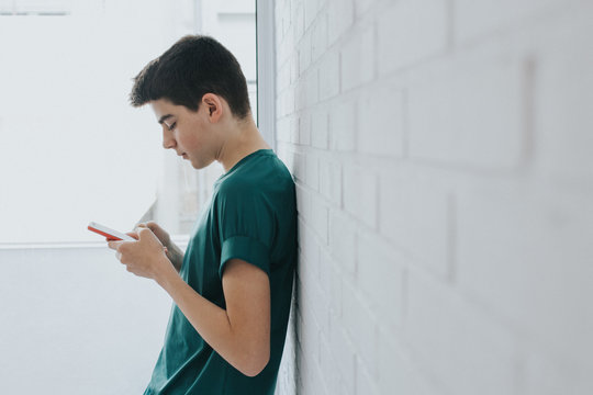 young or teen with mobile phone on the wall