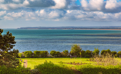 Fototapeta na wymiar View over the sea towards Deal and Sandwich in Kent, UK whilst the sun shines on a park rose garden area of the Royal Esplanade, Ramsgate.