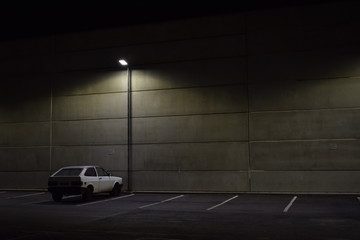 Carro branco em estacionamento de noite. Iluminação publica. Iluminação do estacionamento de...
